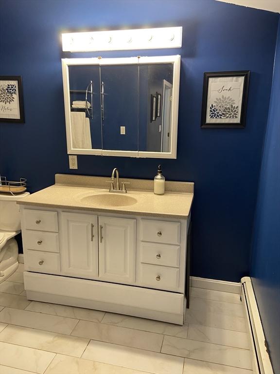 bathroom featuring toilet, baseboard heating, and vanity