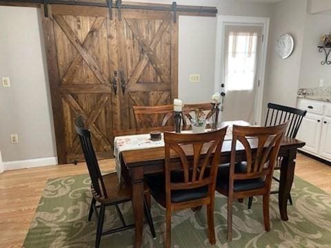 dining room with light wood-type flooring and a barn door