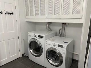 laundry room featuring cabinets, washing machine and dryer, and dark tile patterned flooring