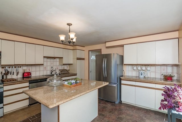 kitchen with backsplash, appliances with stainless steel finishes, hanging light fixtures, a sink, and an inviting chandelier