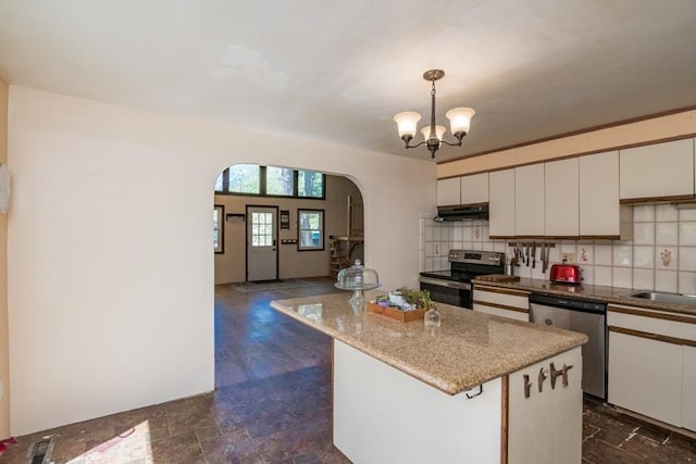 kitchen with decorative backsplash, white cabinetry, under cabinet range hood, arched walkways, and stainless steel appliances