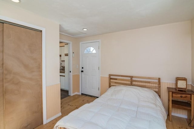 bedroom featuring recessed lighting, wainscoting, light wood finished floors, and wooden walls