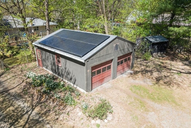 detached garage featuring driveway and solar panels