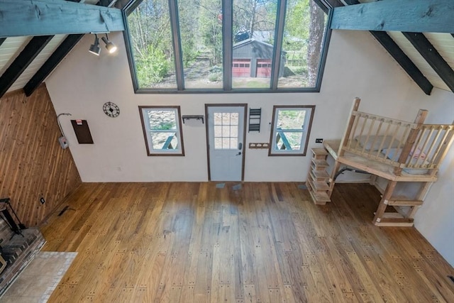 interior space with hardwood / wood-style floors, high vaulted ceiling, wooden walls, and beam ceiling