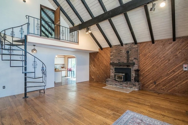 unfurnished living room with arched walkways, wood-type flooring, wood walls, and stairs