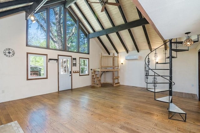 unfurnished living room with beam ceiling, a wall mounted air conditioner, high vaulted ceiling, wood-type flooring, and stairs