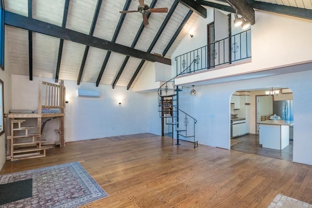 unfurnished living room with stairway, arched walkways, ceiling fan, and hardwood / wood-style flooring