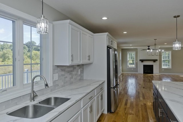 kitchen featuring a fireplace, a sink, white cabinets, open floor plan, and freestanding refrigerator