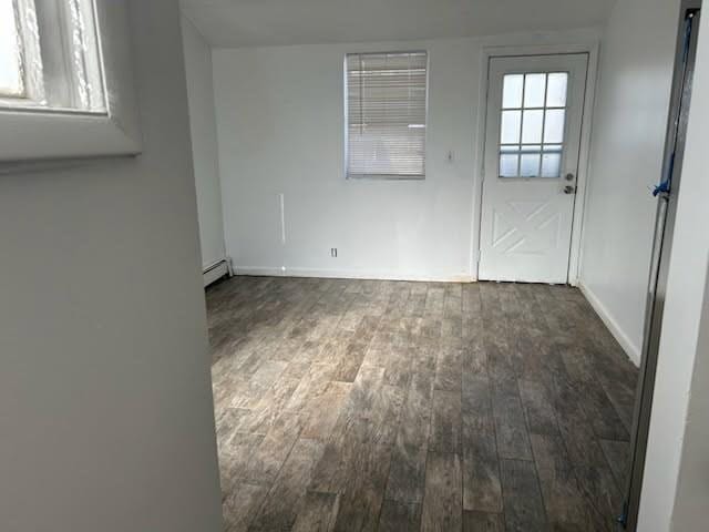 empty room featuring dark wood-style floors, baseboards, and baseboard heating