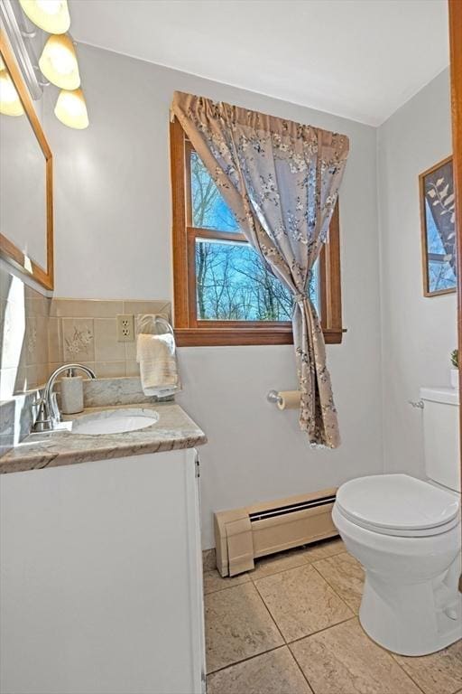 half bath featuring tile patterned flooring, toilet, vanity, and a baseboard radiator