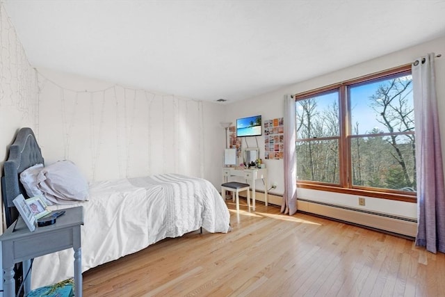 bedroom with hardwood / wood-style floors and a baseboard heating unit