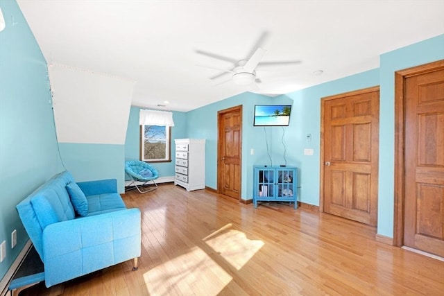 living area with ceiling fan, light wood-type flooring, and baseboards