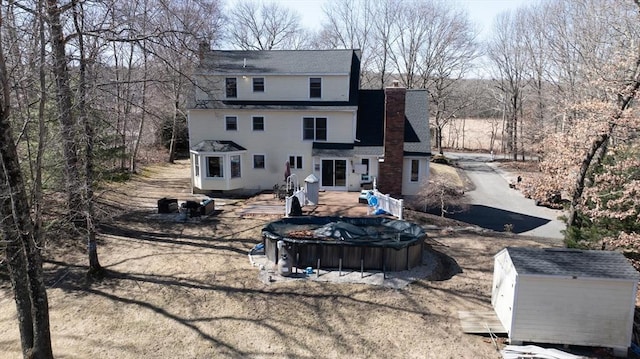 back of house with an outbuilding, a chimney, and a storage shed