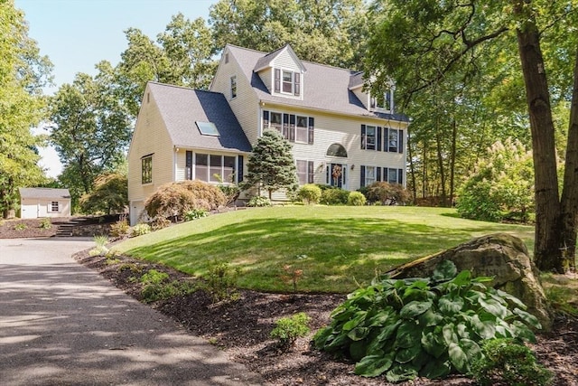 colonial inspired home featuring a front lawn and a shingled roof