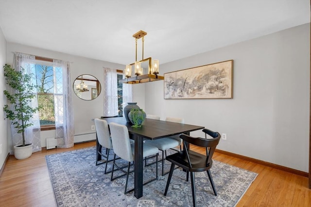 dining space featuring light wood-type flooring, baseboards, and a baseboard radiator