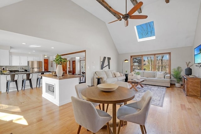 dining area featuring high vaulted ceiling, a skylight, and light wood finished floors