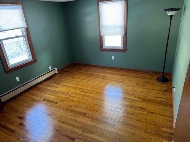 unfurnished room featuring baseboard heating and light hardwood / wood-style flooring