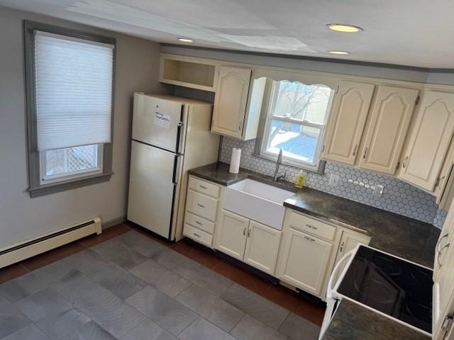 kitchen featuring sink, electric range oven, a baseboard heating unit, fridge, and tasteful backsplash