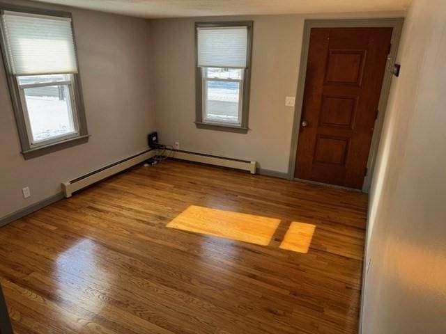 empty room with hardwood / wood-style floors and a baseboard radiator