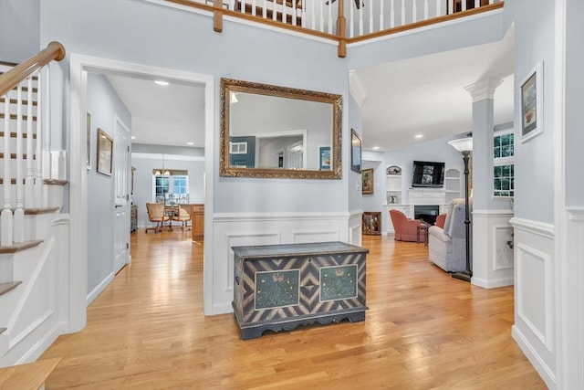 hall with ornate columns and light hardwood / wood-style flooring