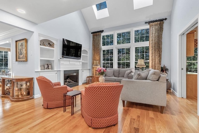 living room featuring a towering ceiling, built in features, a skylight, and light hardwood / wood-style flooring