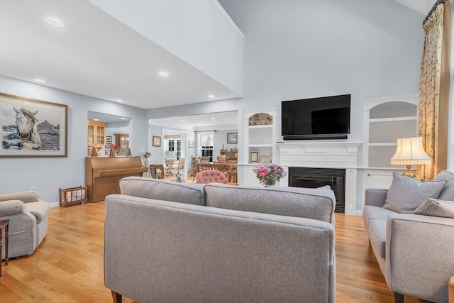 living room with built in shelves and light wood-type flooring