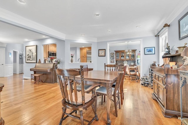 dining room with ornamental molding and light hardwood / wood-style floors