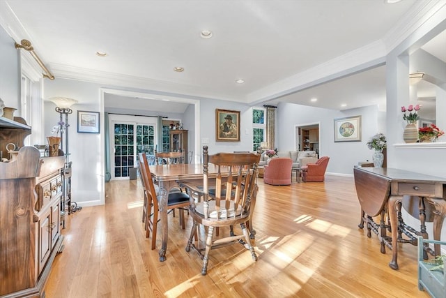 dining space with ornamental molding and light wood-type flooring