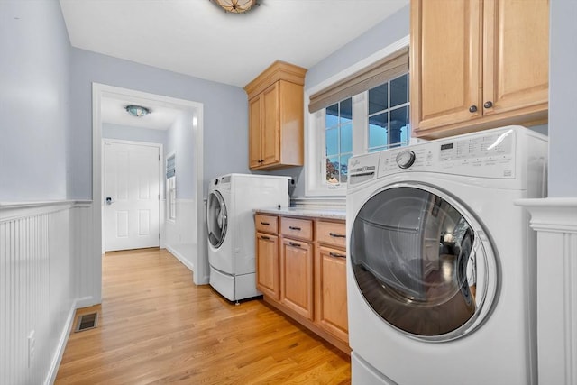 laundry area with light hardwood / wood-style floors, cabinets, and washer and clothes dryer