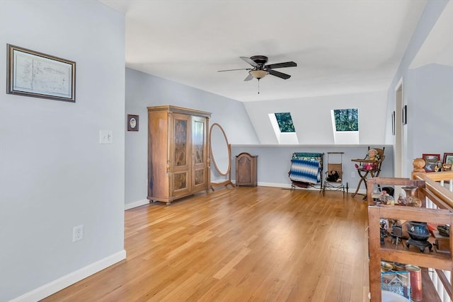 interior space with ceiling fan, light hardwood / wood-style floors, and vaulted ceiling with skylight