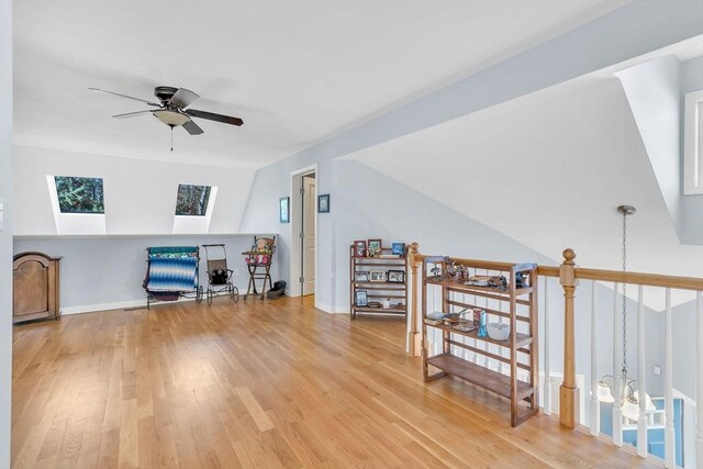 additional living space with wood-type flooring, ceiling fan, and vaulted ceiling with skylight