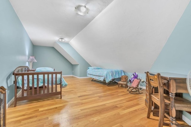 bedroom with light wood-type flooring and vaulted ceiling