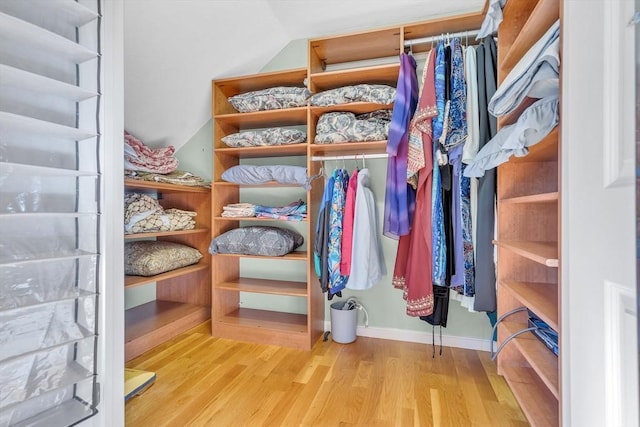 walk in closet with light wood-type flooring and vaulted ceiling