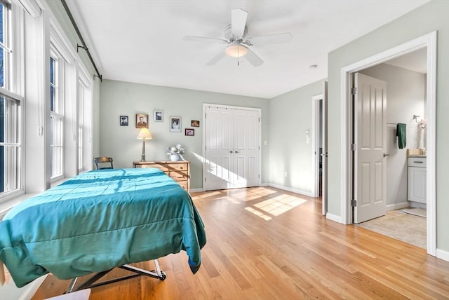 bedroom featuring ceiling fan, light wood-type flooring, ensuite bathroom, and a closet