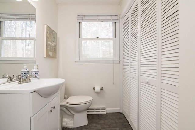 bathroom with tile patterned floors, toilet, a baseboard heating unit, a closet, and vanity