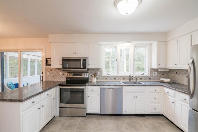 kitchen featuring a sink, backsplash, white cabinetry, appliances with stainless steel finishes, and a peninsula