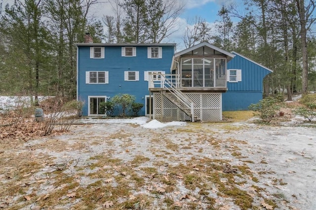 rear view of house featuring stairs, a sunroom, and a chimney