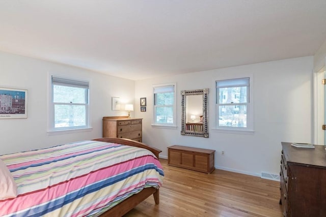 bedroom with wood finished floors, visible vents, and baseboards