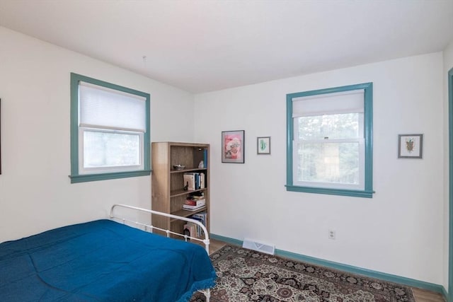 bedroom featuring visible vents, multiple windows, and baseboards