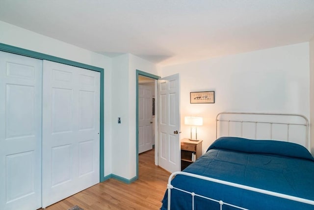 bedroom featuring light wood finished floors, baseboards, and a closet