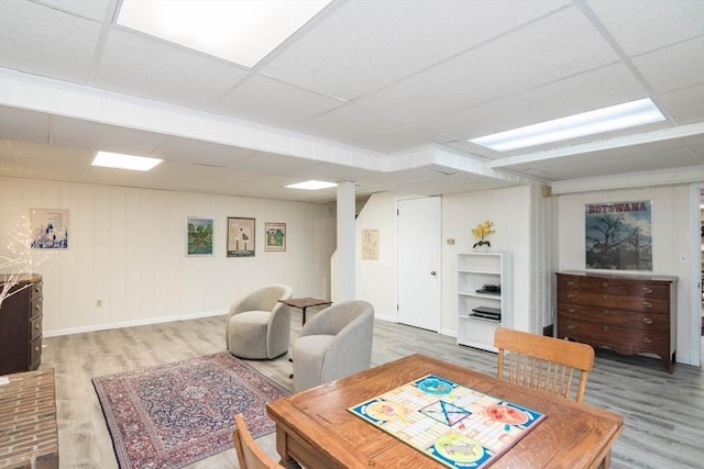 dining area with light wood-style floors, baseboards, and a paneled ceiling