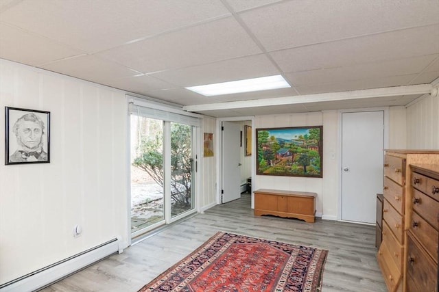 interior space featuring a baseboard radiator, a paneled ceiling, and light wood-style floors