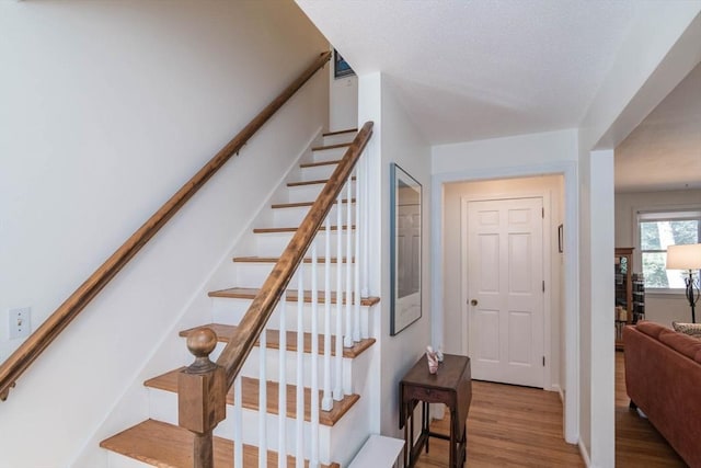 staircase featuring a textured ceiling and wood finished floors