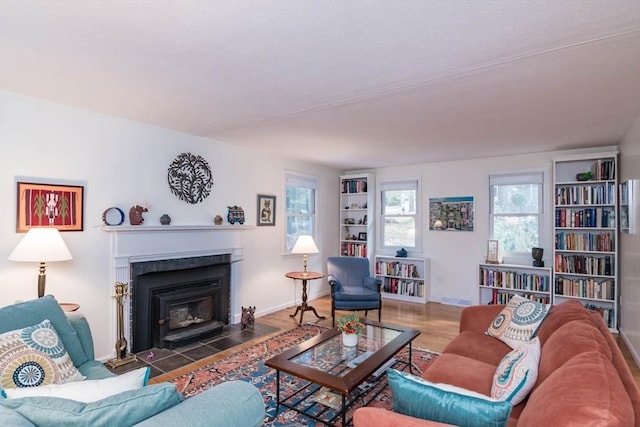 living area with a fireplace with flush hearth, baseboards, and wood finished floors