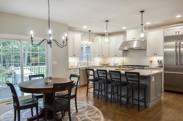 kitchen featuring stainless steel appliances, white cabinetry, a center island, and extractor fan