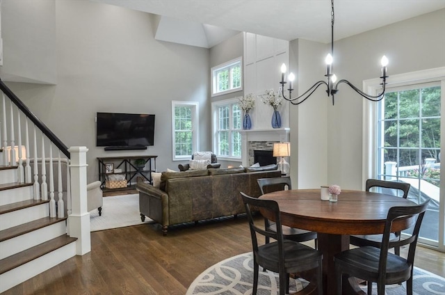 dining space featuring dark hardwood / wood-style flooring, an inviting chandelier, and a stone fireplace