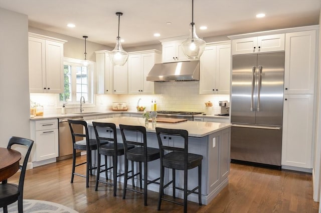 kitchen featuring white cabinets, sink, decorative light fixtures, stainless steel appliances, and extractor fan