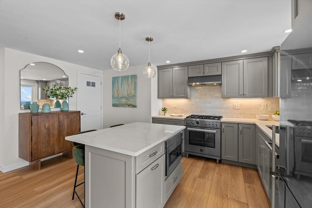 kitchen with gray cabinets, light wood-style floors, stainless steel appliances, and under cabinet range hood
