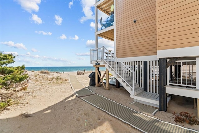 view of side of property with a beach view, stairs, and a water view
