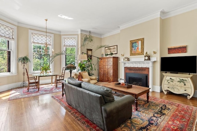living room with wood finished floors, a fireplace, crown molding, and baseboards